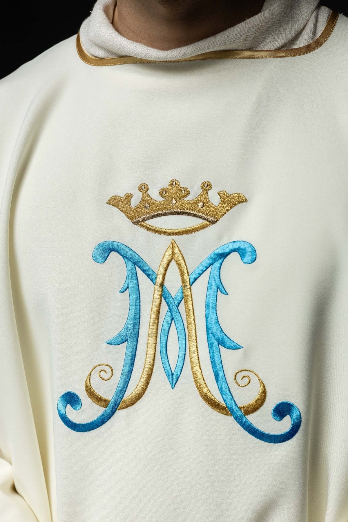 Ecru dalmatic close-up showing gold-trimmed collar and Marian embroidery