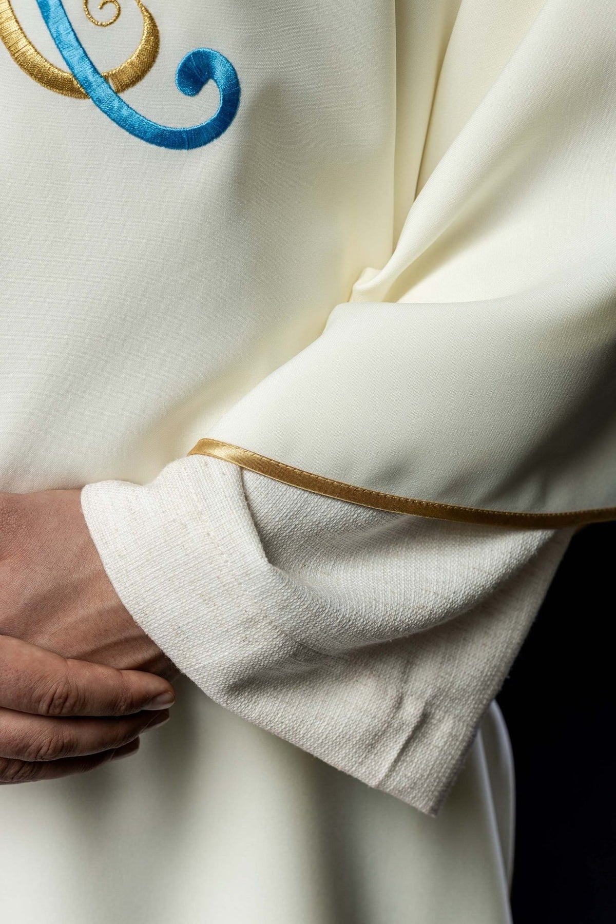 Ecru dalmatic close-up showing Marian embroidery and smooth satin fabric