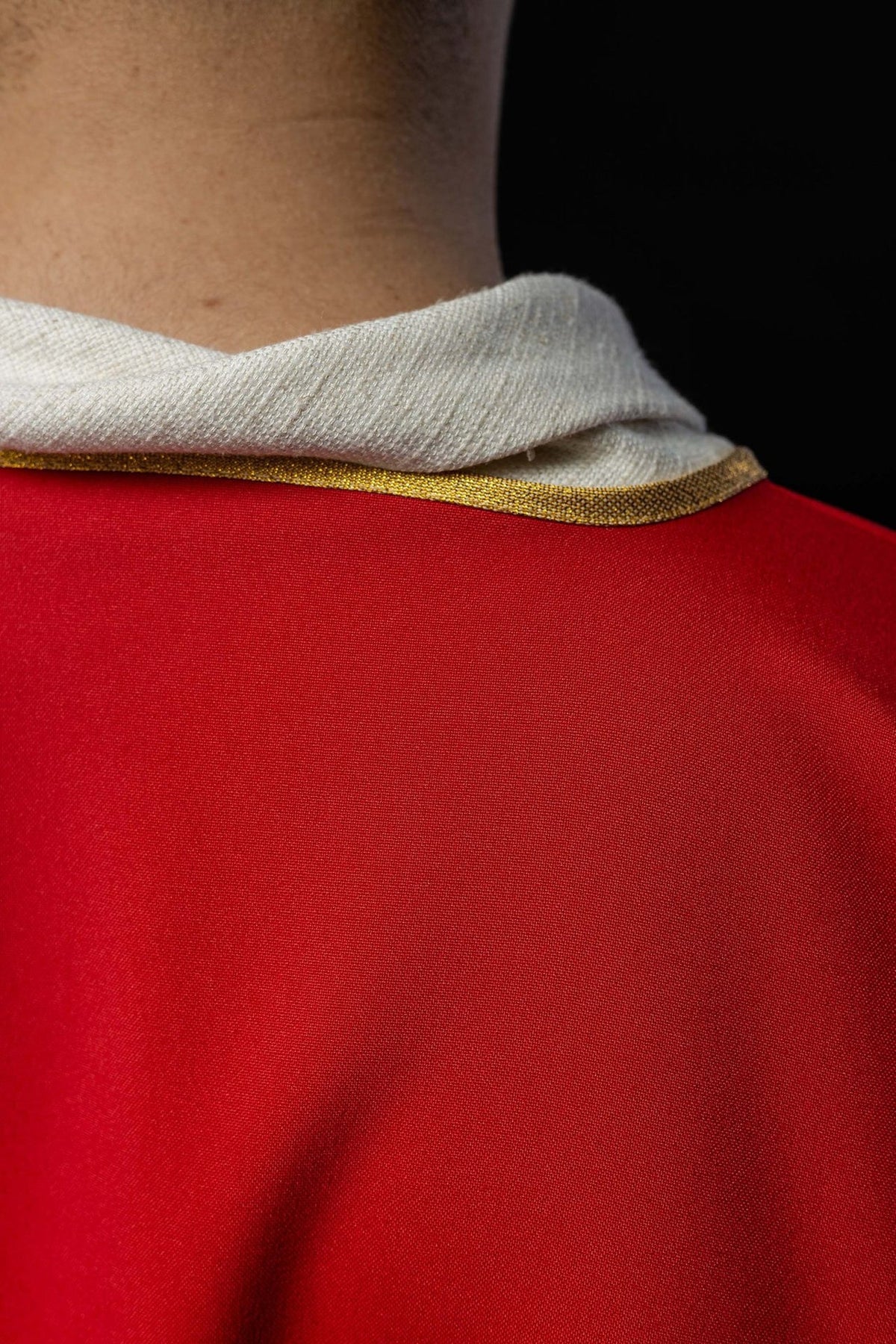 Red dalmatic collar close-up with gold trim and white lining