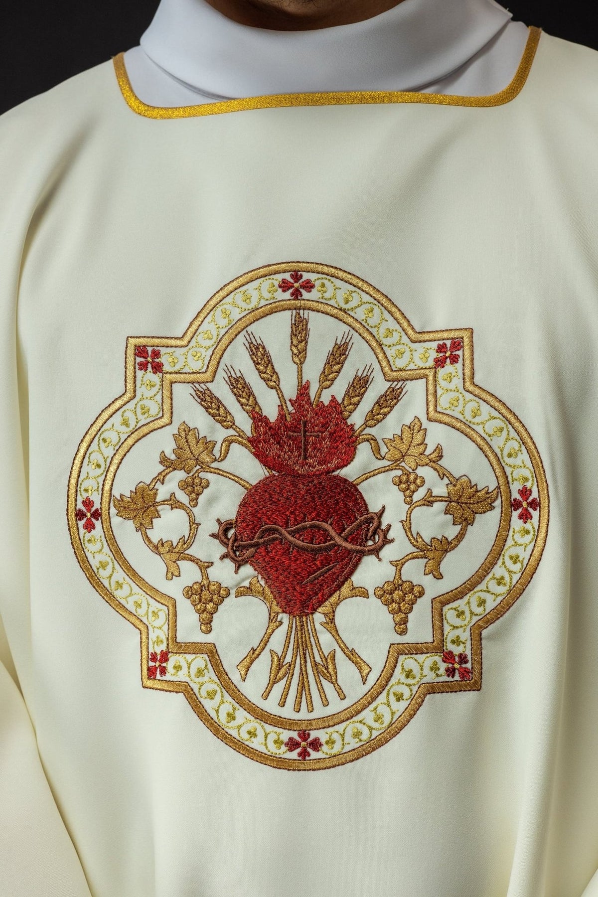 Dalmatic close-up showing ecru fabric, gold trim and Sacred Heart of Jesus embroidery