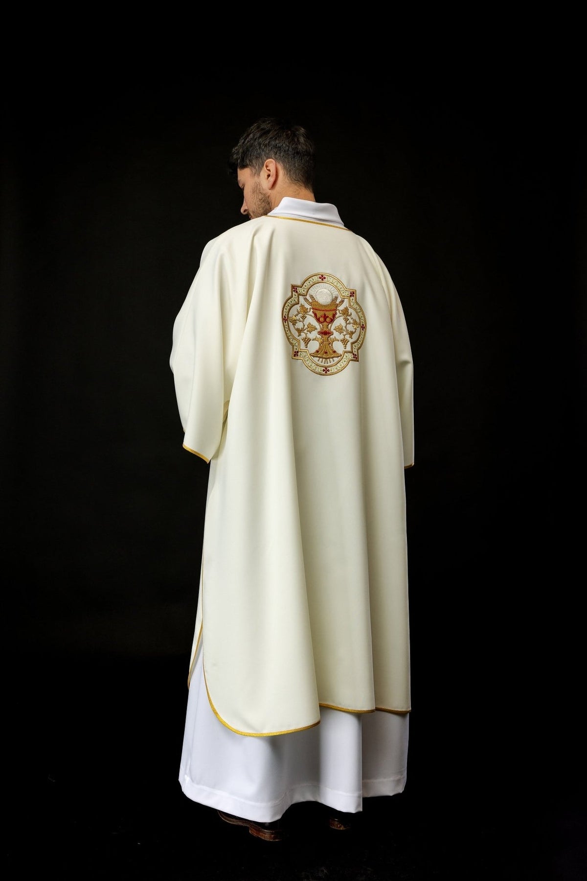 Dalmatic worn from the back, showing ecru fabric and Communion Chalice embroidery