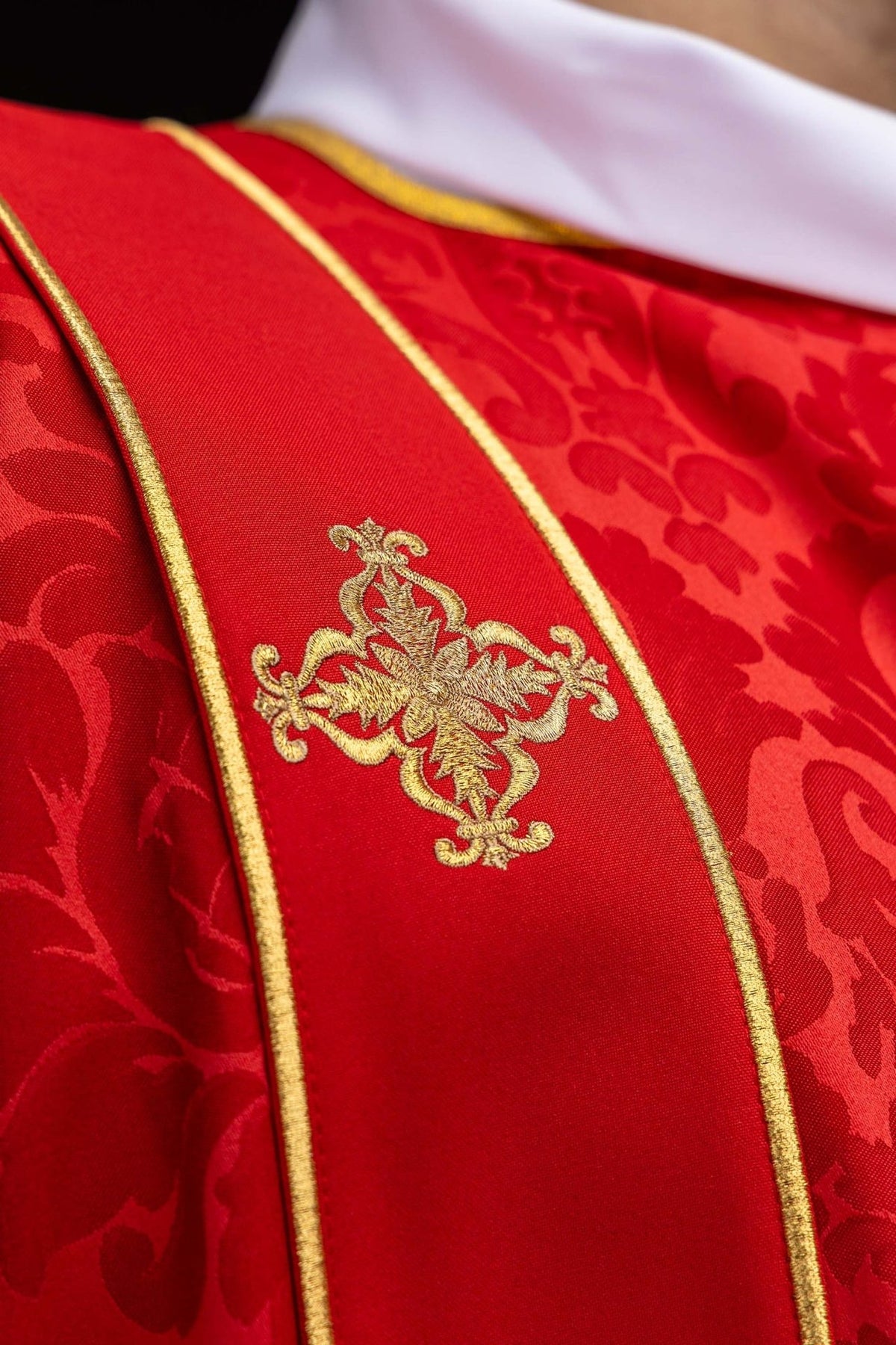 Red dalmatic close-up of an embroidered gold cross on the orphrey