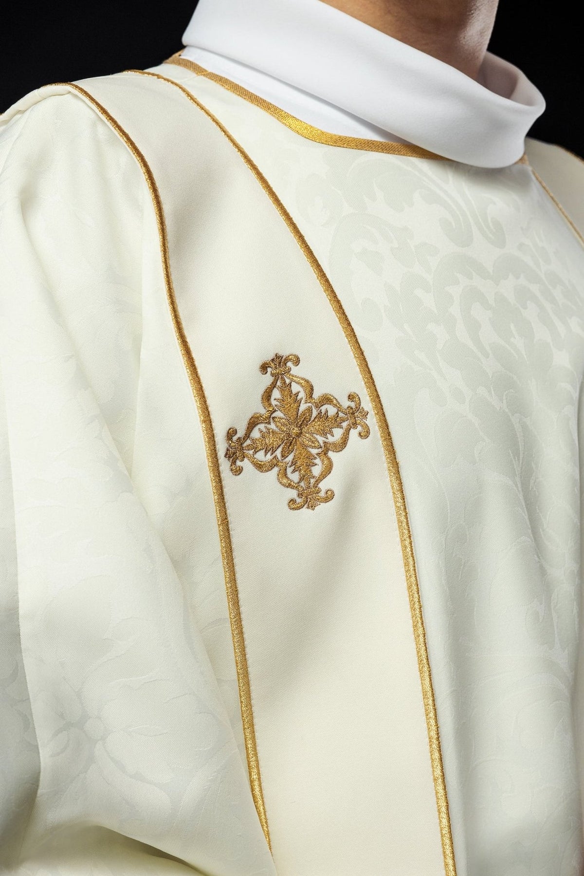 Ecru dalmatic close-up showing jacquard fabric and gold embroidered cross