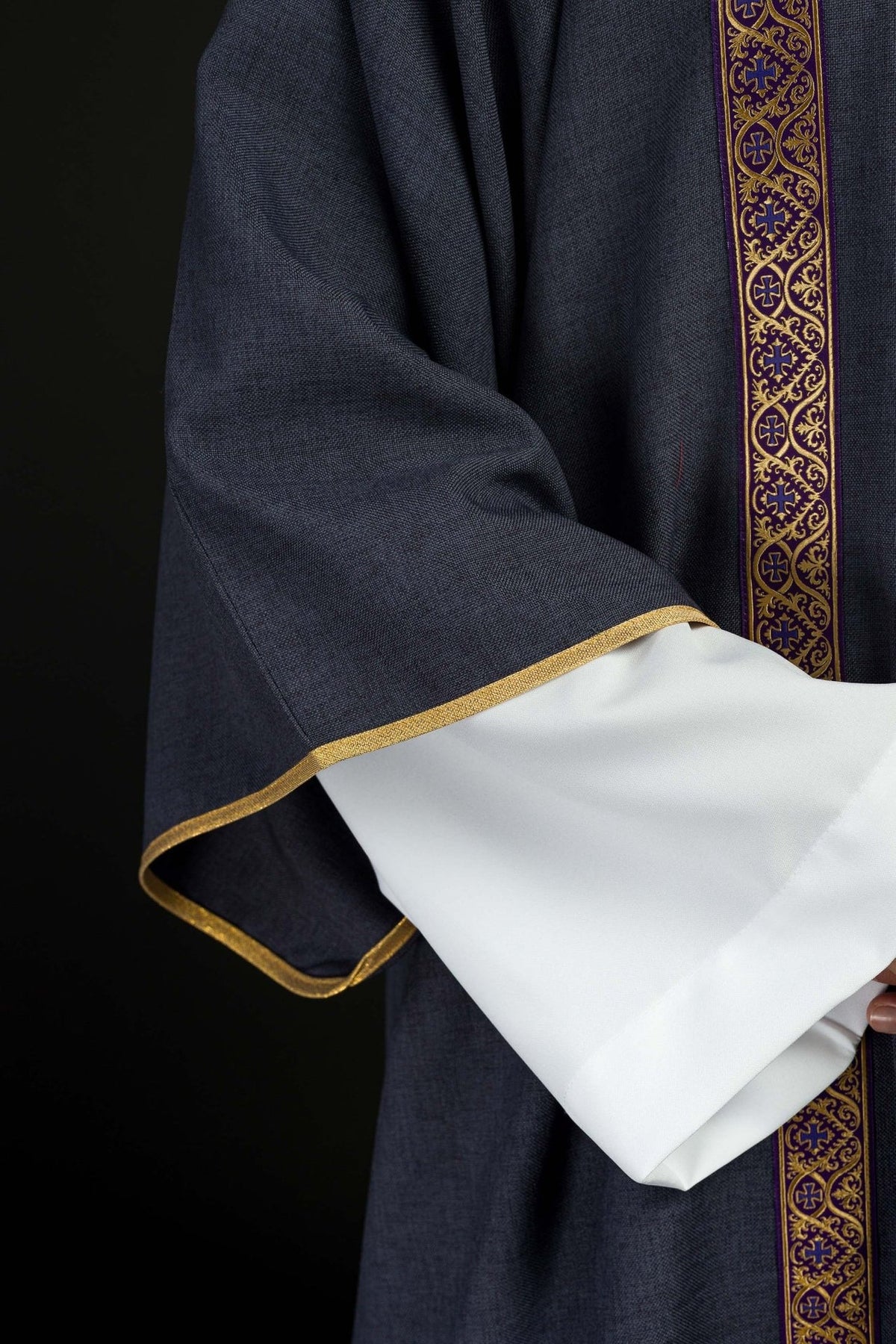 Purple dalmatic sleeve close-up with gold trim and white cuff visible