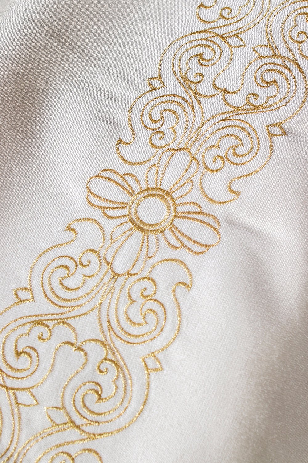 Liturgical veil close-up showing gold floral embroidery on ivory fabric