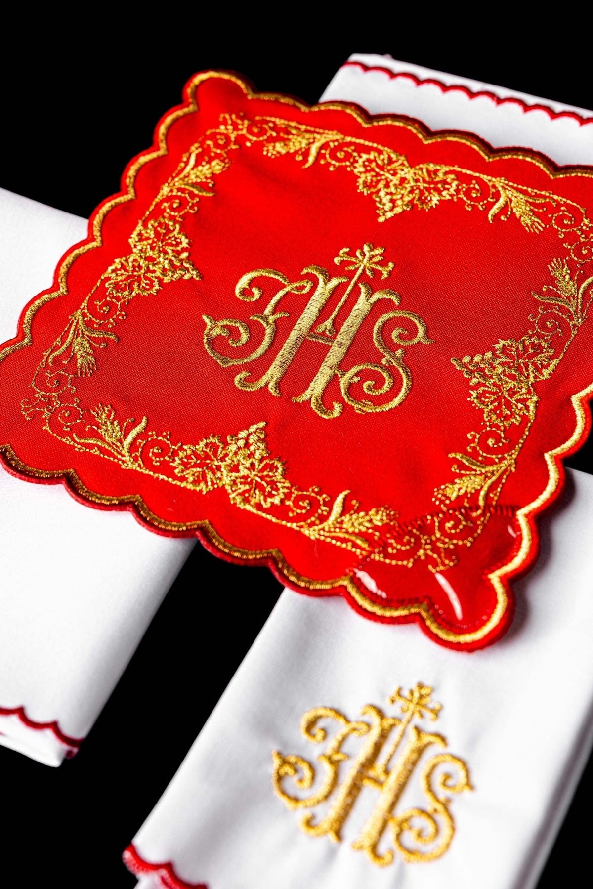Red chalice pall close-up with gold embroidered IHS and floral border
