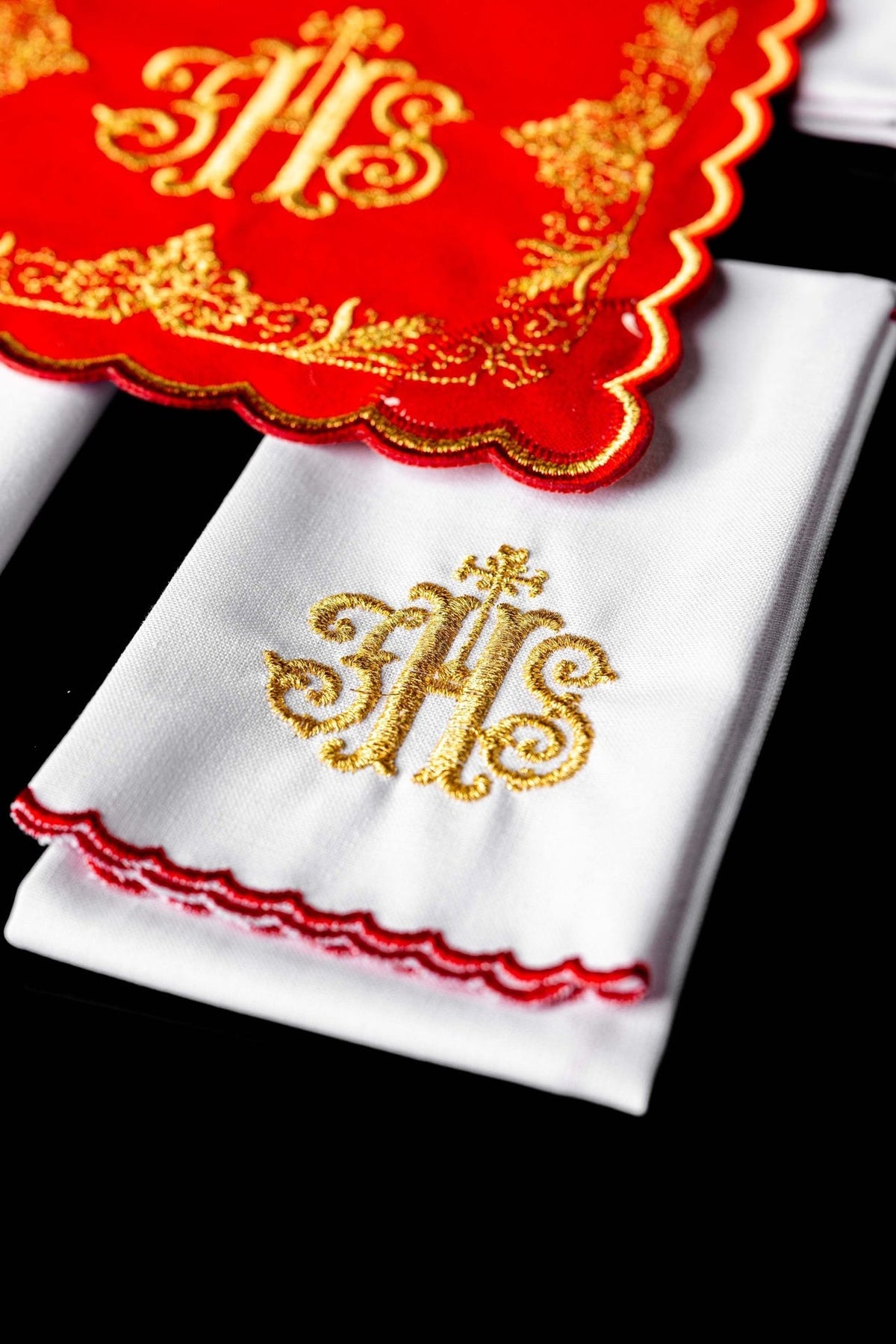 White altar linen close-up with gold embroidered IHS and red scalloped trim