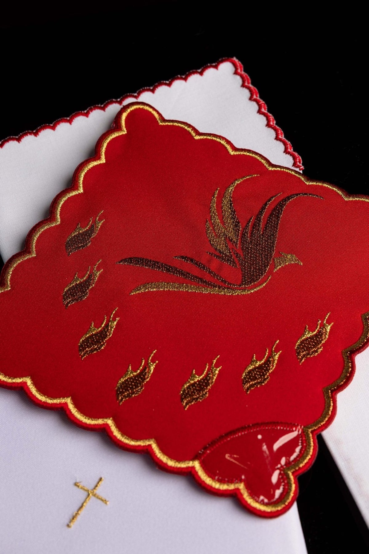 Altar linen set close-up showing red chalice pall with embroidered Holy Spirit and gold border