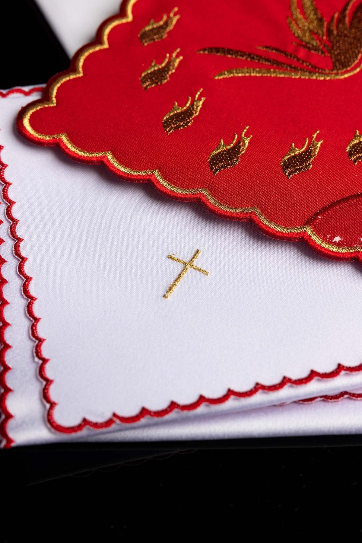 Altar linen set close-up showing embroidered red chalice pall, gold cross, and scalloped edges