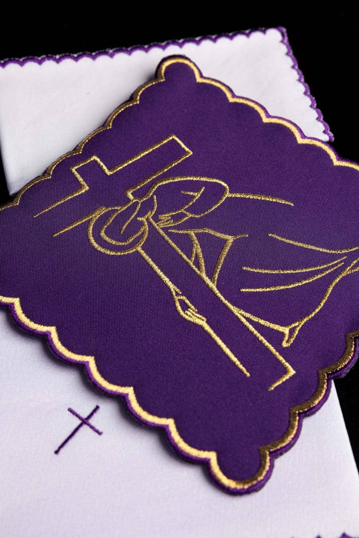 Altar linen set close-up showing purple and gold embroidered Station of the Cross motif