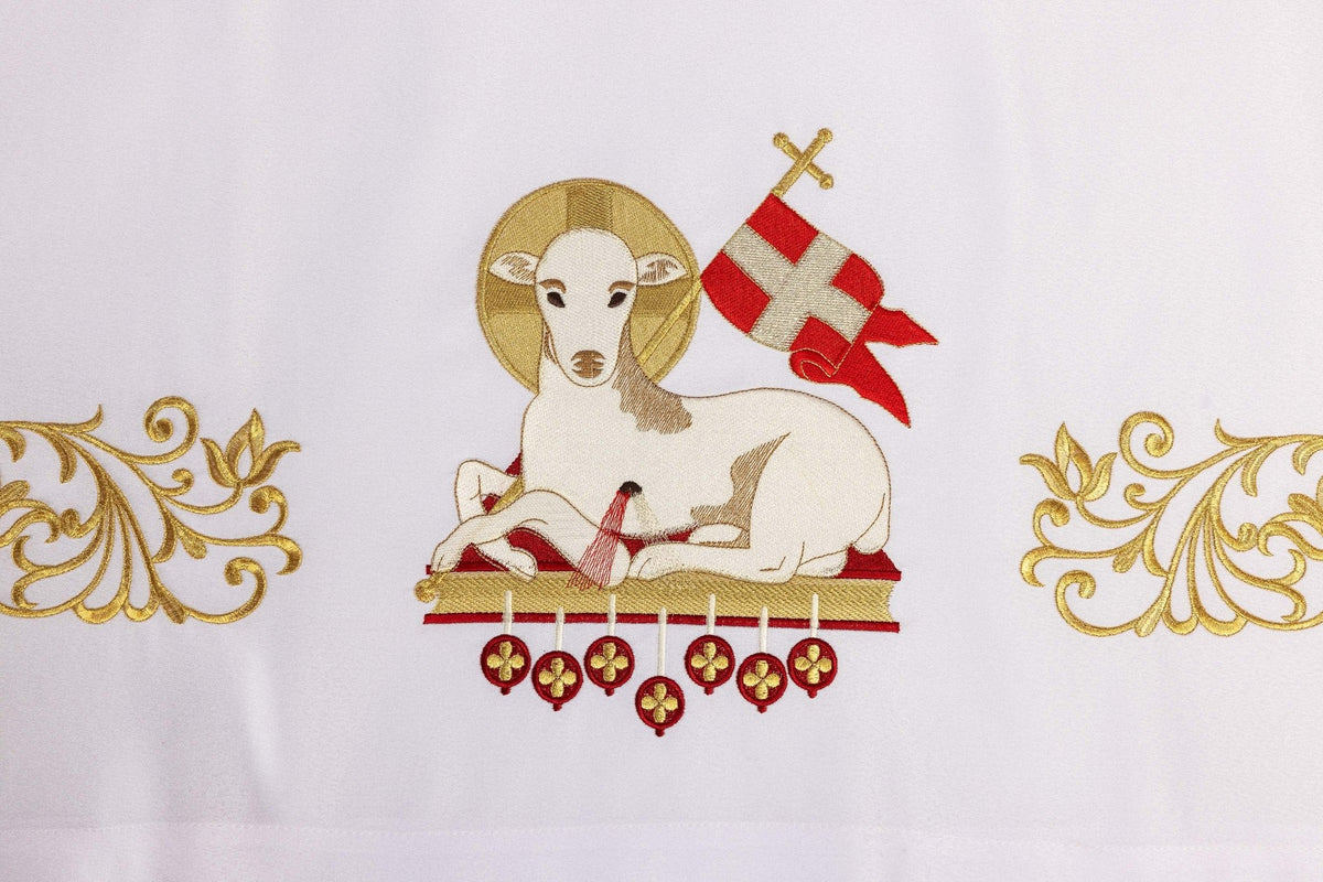White altar cloth close-up showing Agnus Dei embroidery with red and gold details