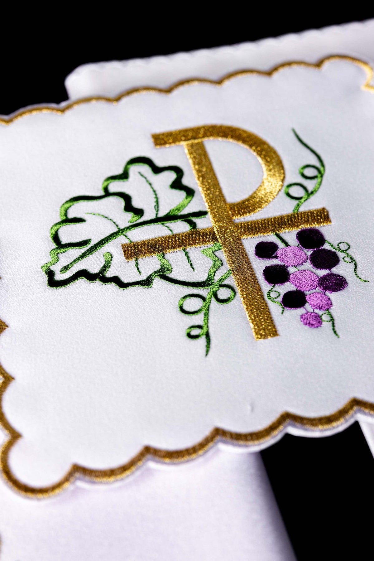 Altar linen set detail of gold PAX embroidery with green leaves and purple grapes on white linen