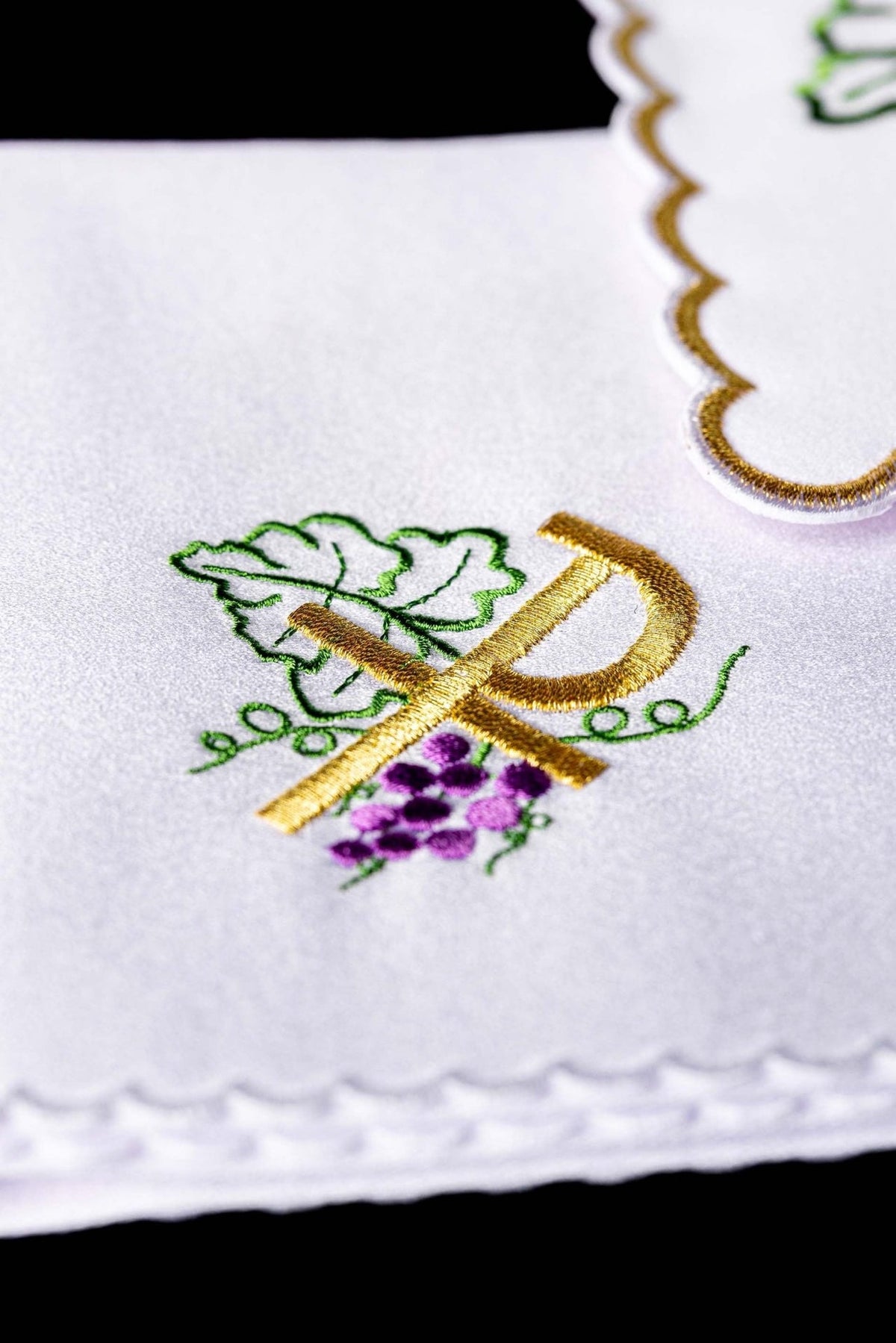 Altar linen set close-up showing embroidered PAX and grapes on a white linen edge