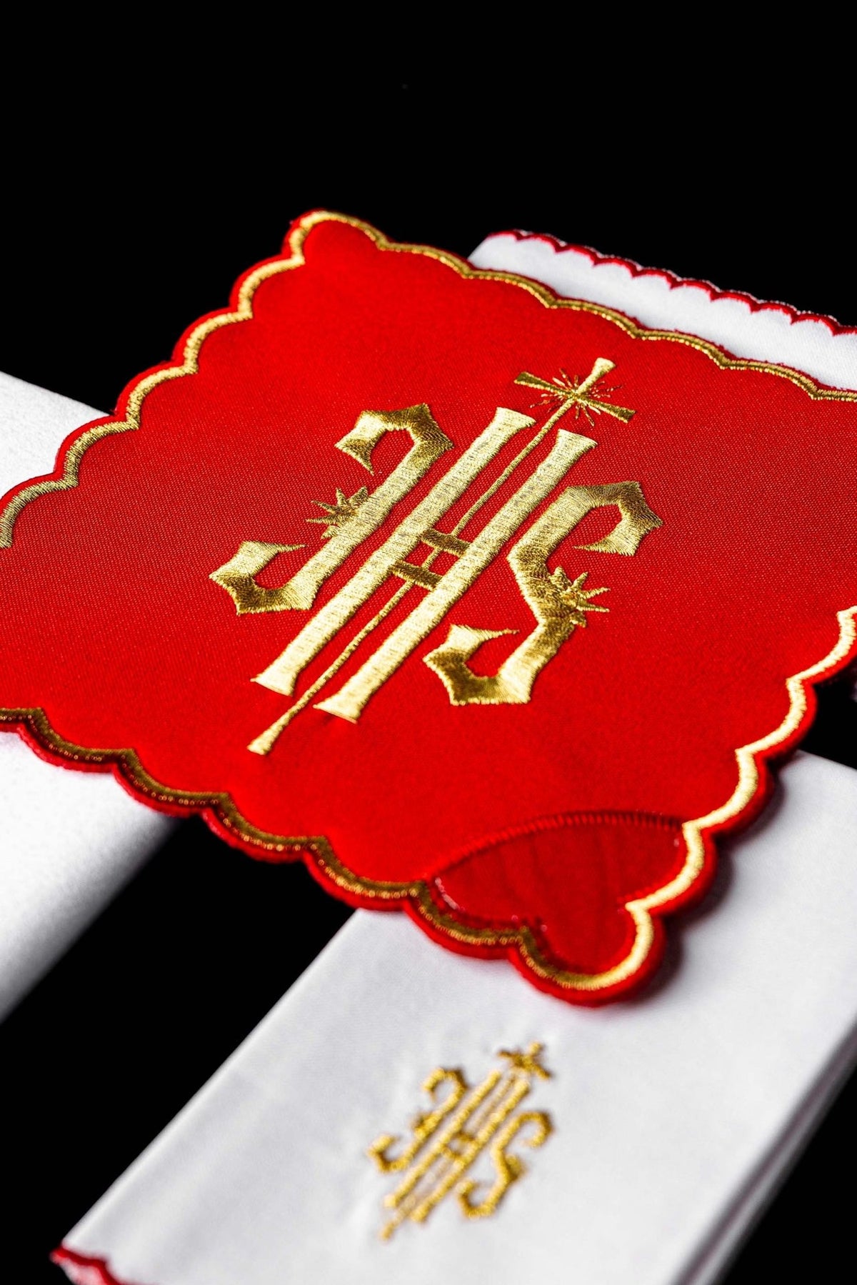 Altar linen set close-up showing red chalice pall with gold embroidered IHS