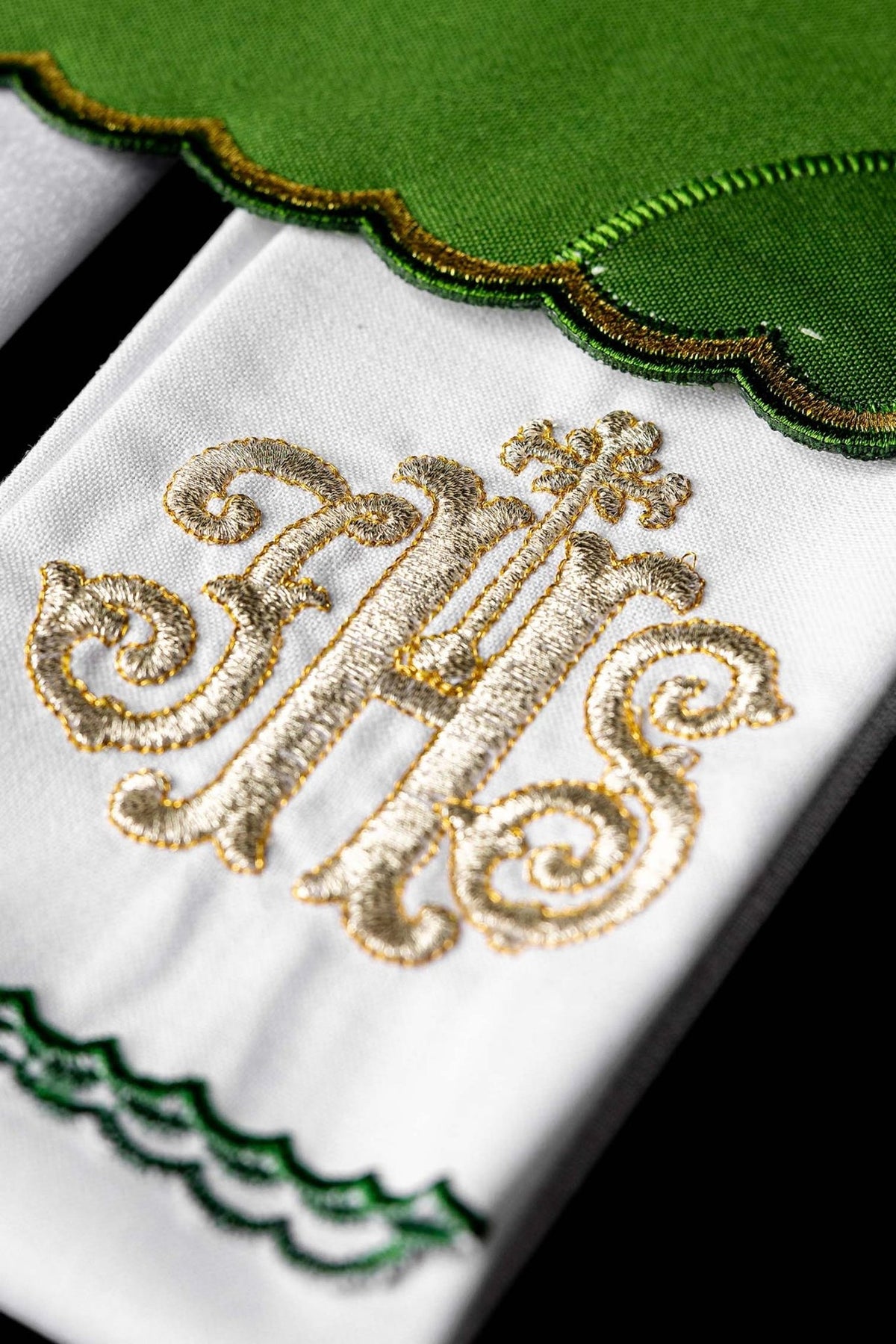 White purificator close-up with gold IHS embroidery and green scalloped edging