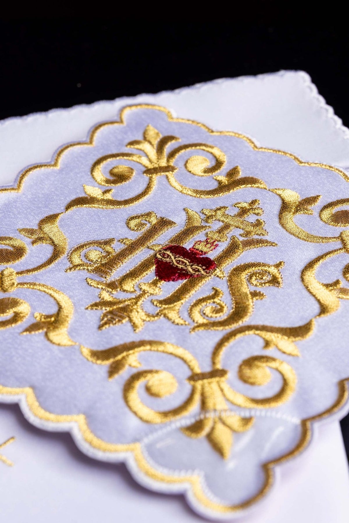 Altar linen set close-up showing gold IHS embroidery with a red heart and ornate scrollwork