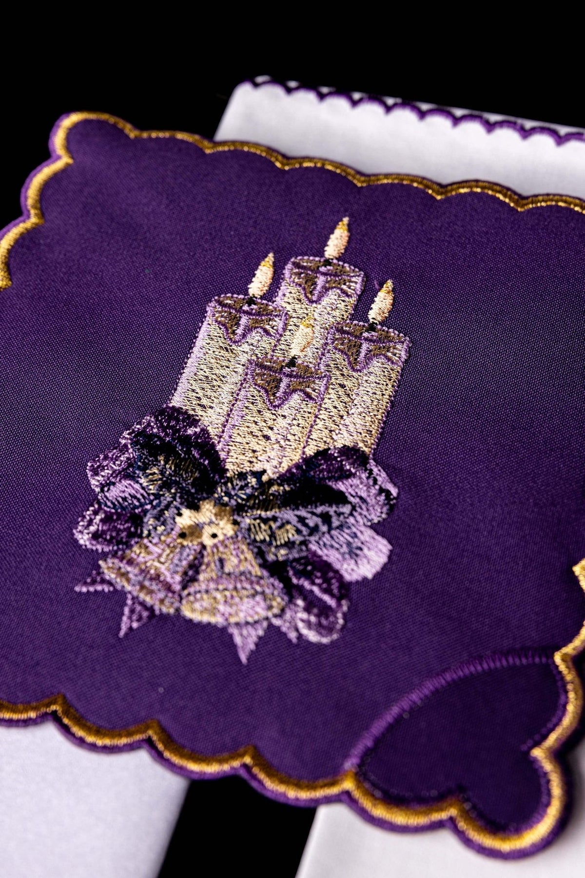 Altar linen set close-up showing embroidered purple chalice pall with three candles