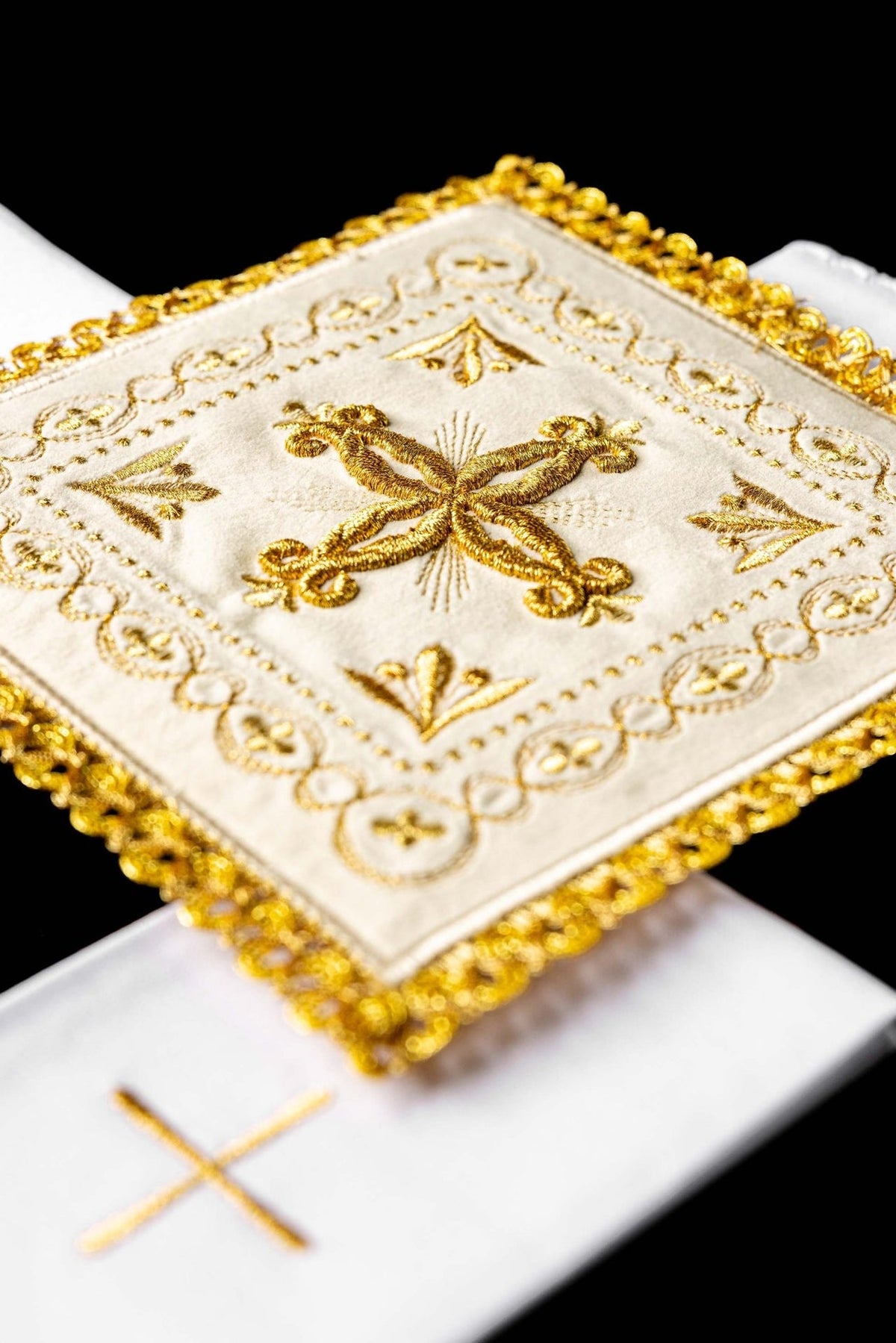 Altar linen set close-up showing gold embroidered cross on the ecru corporal