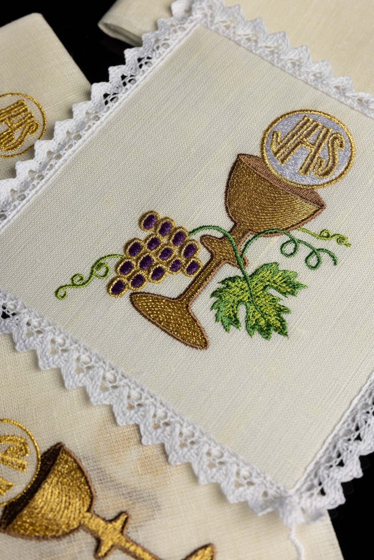 Altar linen set close-up of embroidered gold chalice, grapes and green leaves on cream linen