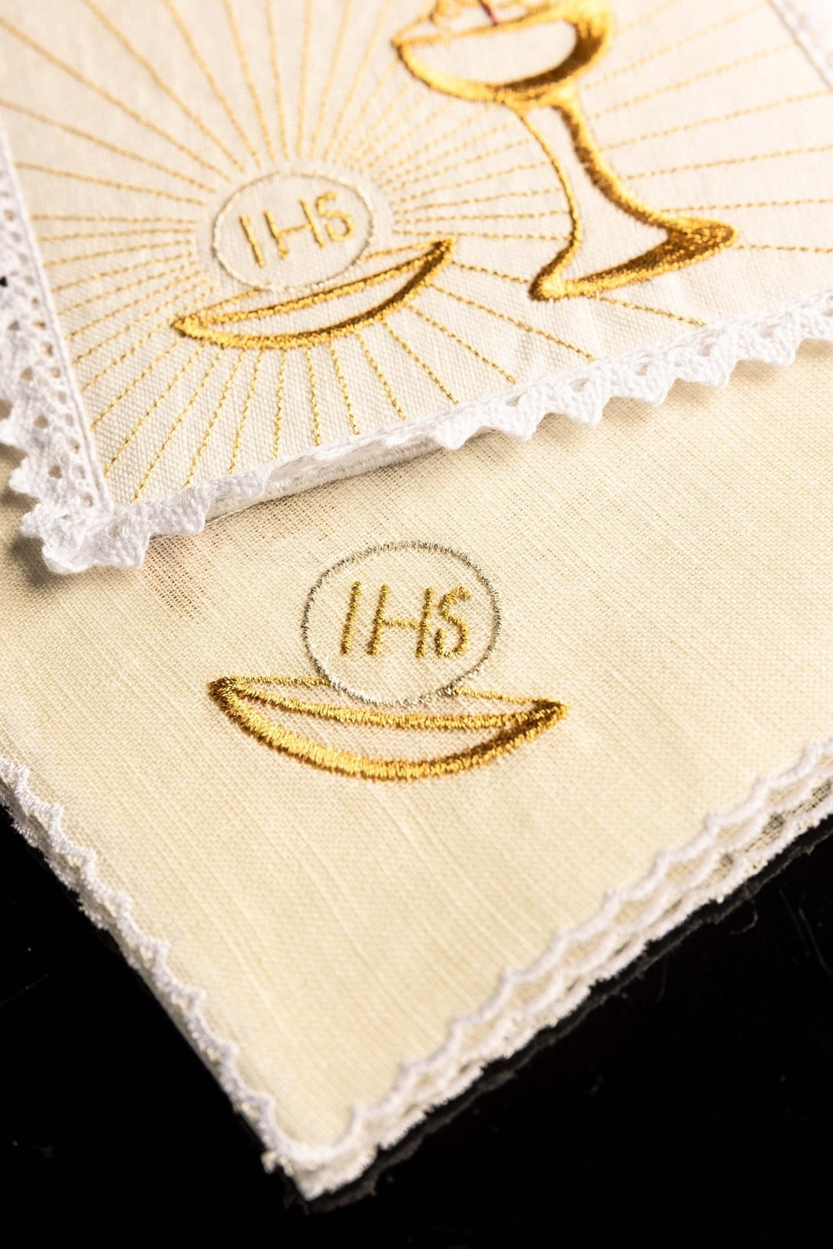 Altar linen set folded, showing gold embroidered IHS host motif and lace edging