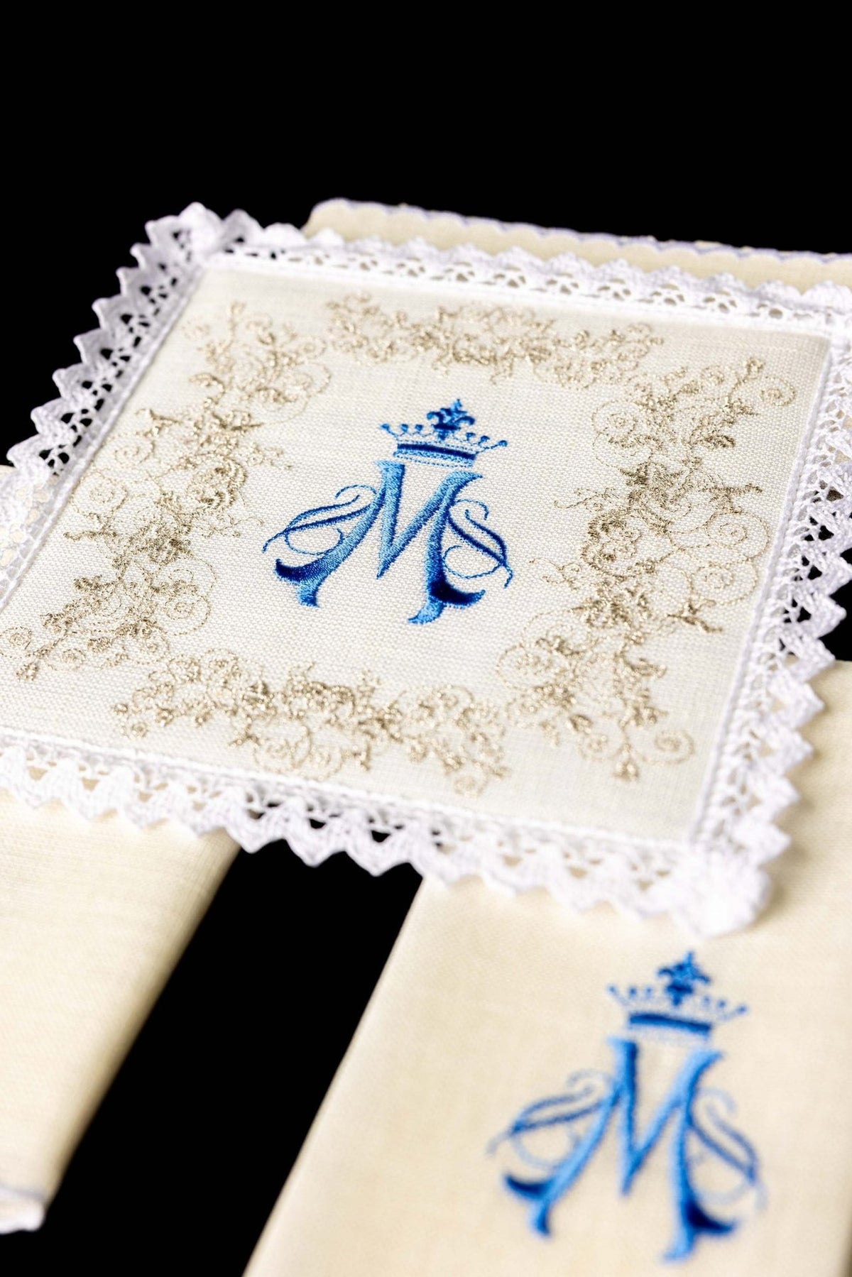 Altar linen set close-up showing embroidered blue Marian symbol, ornate embroidery and lace edging