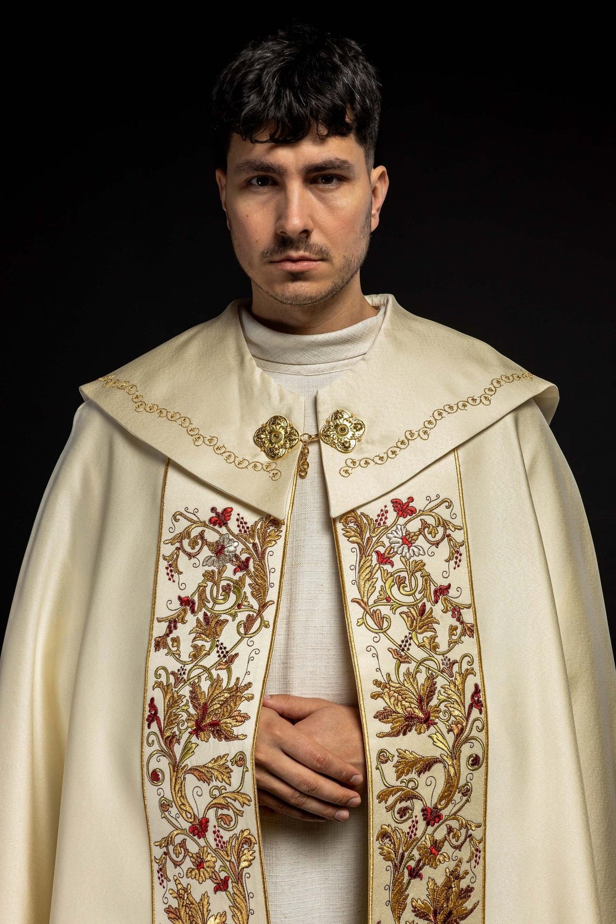 Ecru satin cope worn from the front, with ornate floral embroidery and gold trim