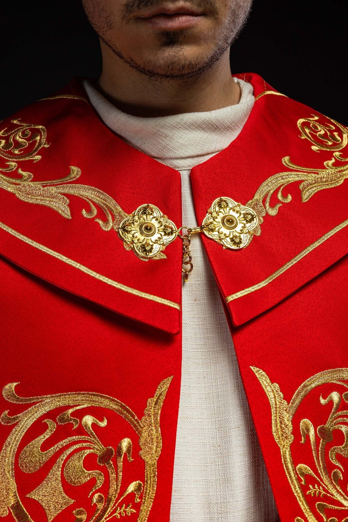 Red cope, close-up of gold floral clasp and embroidered collar