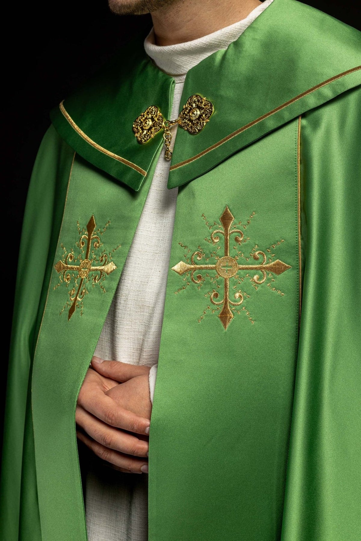 Green cope close-up showing gold cross embroidery and ornate clasp