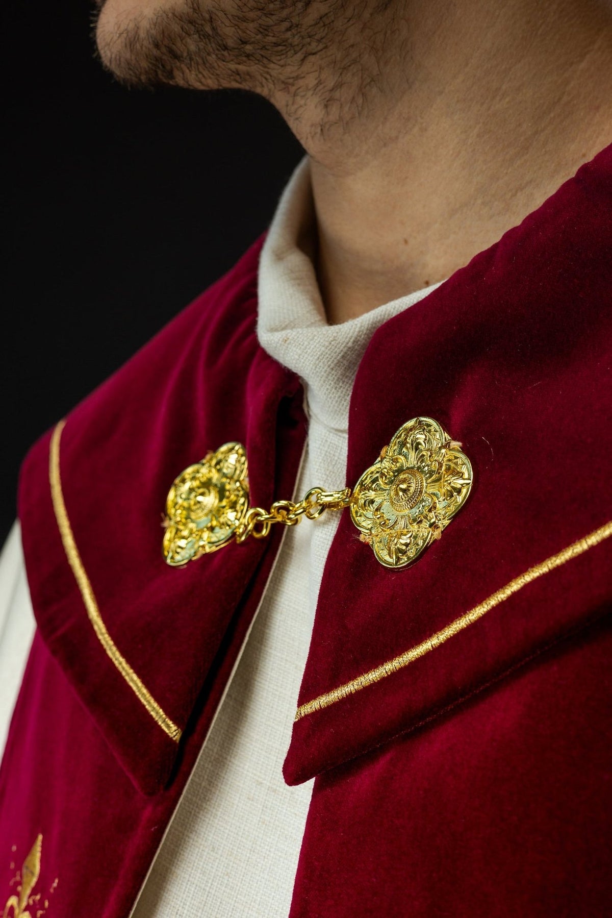 Burgundy velvet cope shoulder close-up with gold trim and ornate clasp