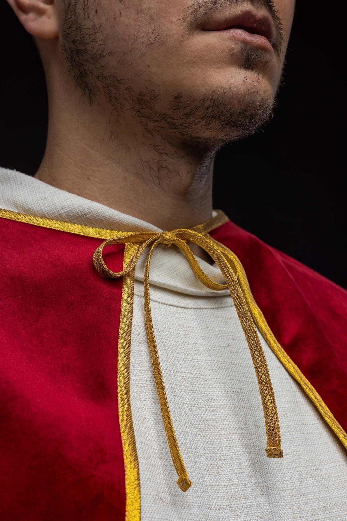 Altar server cape close-up showing the red velvet fabric and gold tie at the neckline