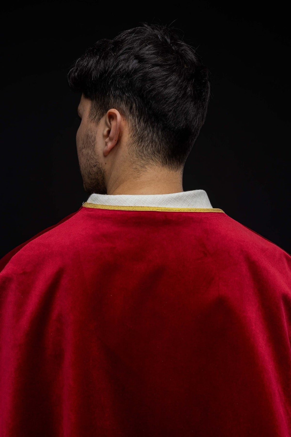 Red altar server cape worn from the back, showing the plain velvet panel and gold neckline trim