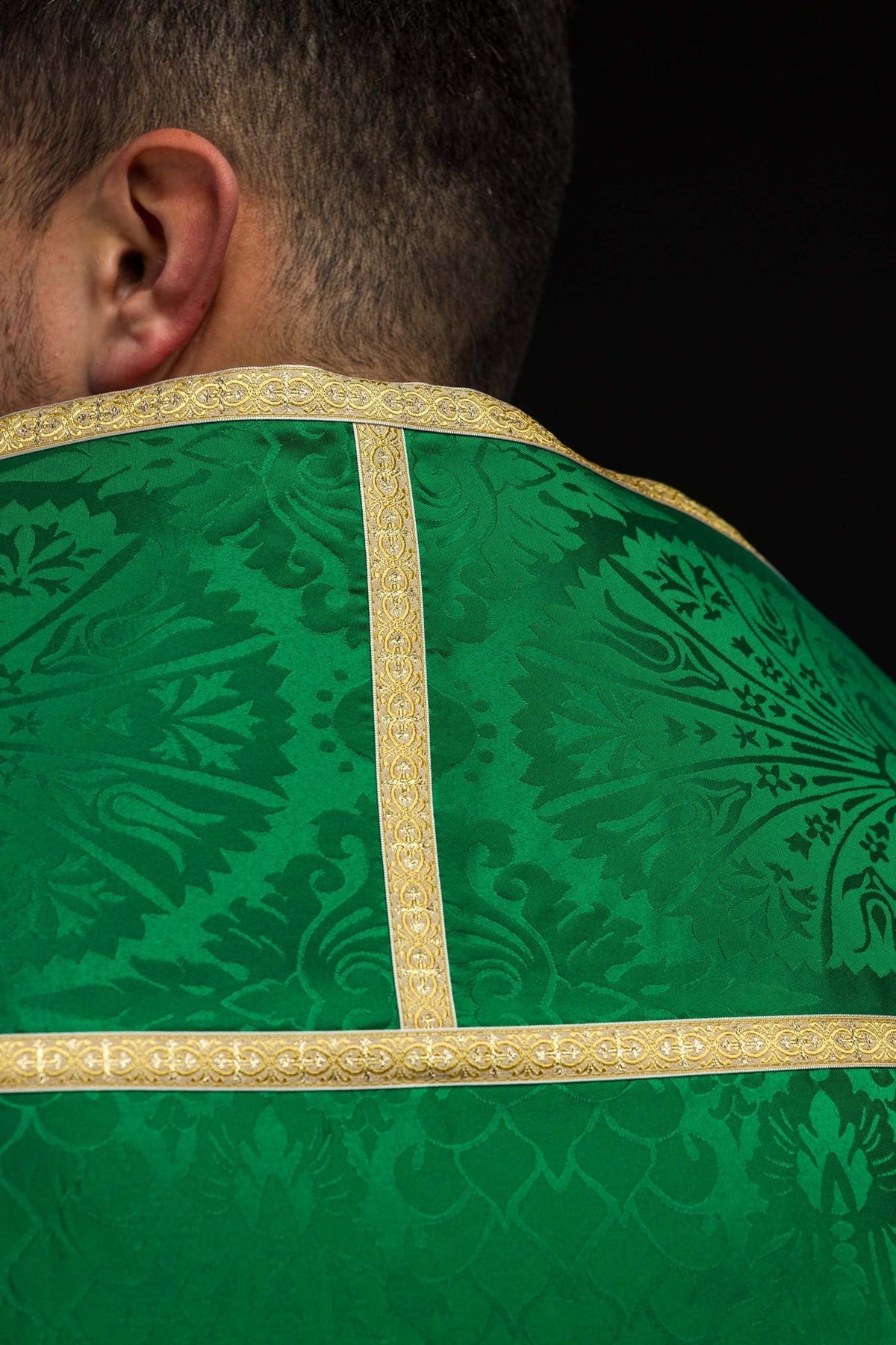 Green jacquard cope detail showing dark woven motifs and ornate gold edging