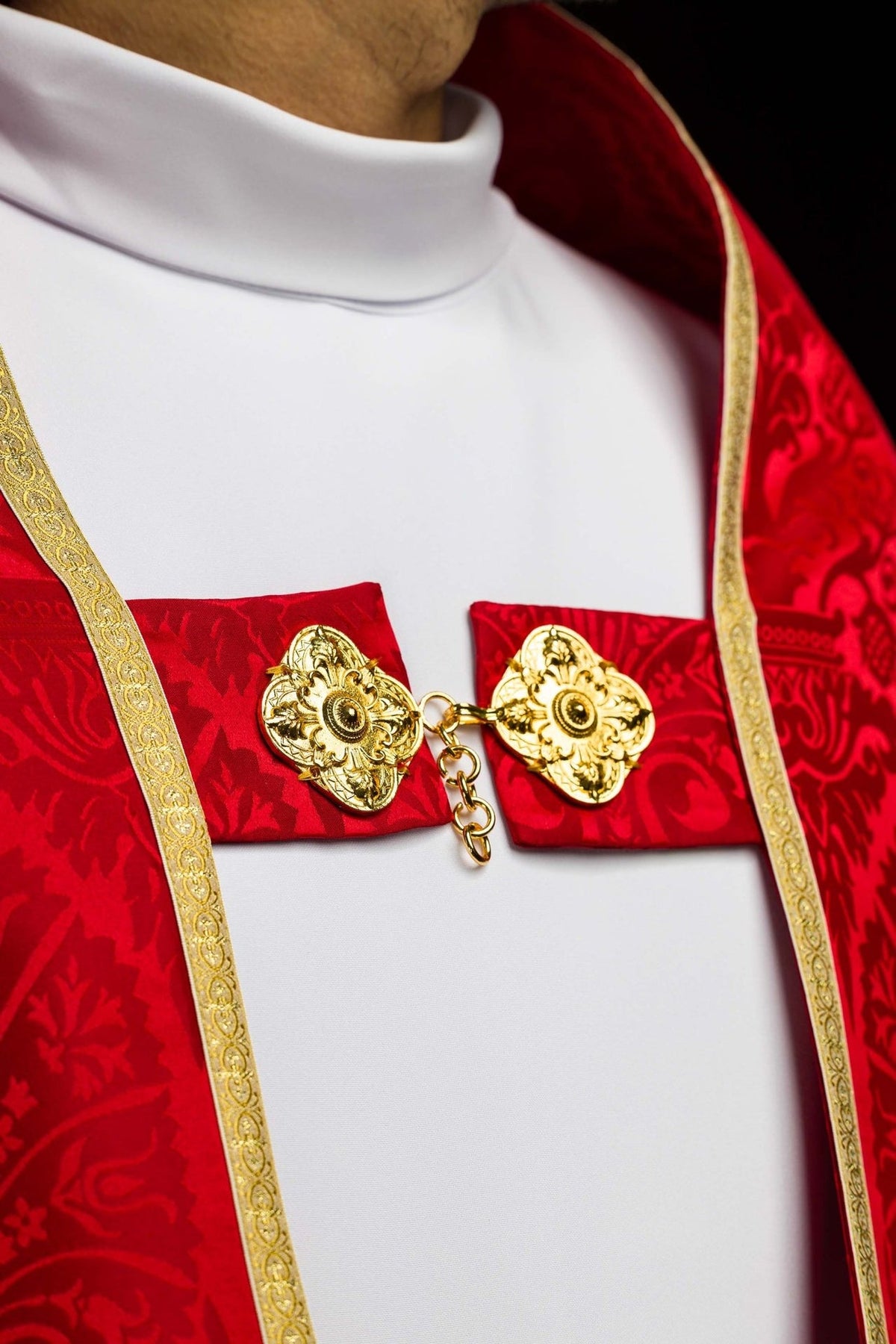 Roman cope chest close-up with red jacquard fabric, gold trim and two ornate gold clasps