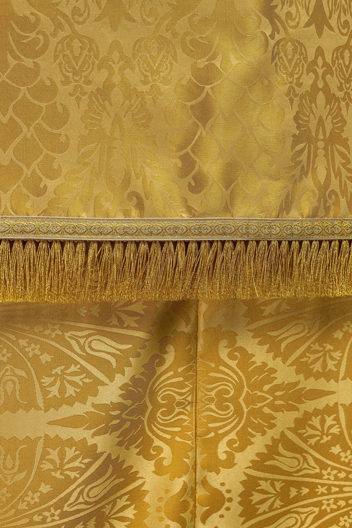 Gold cope hem close-up with patterned trim and gold fringe