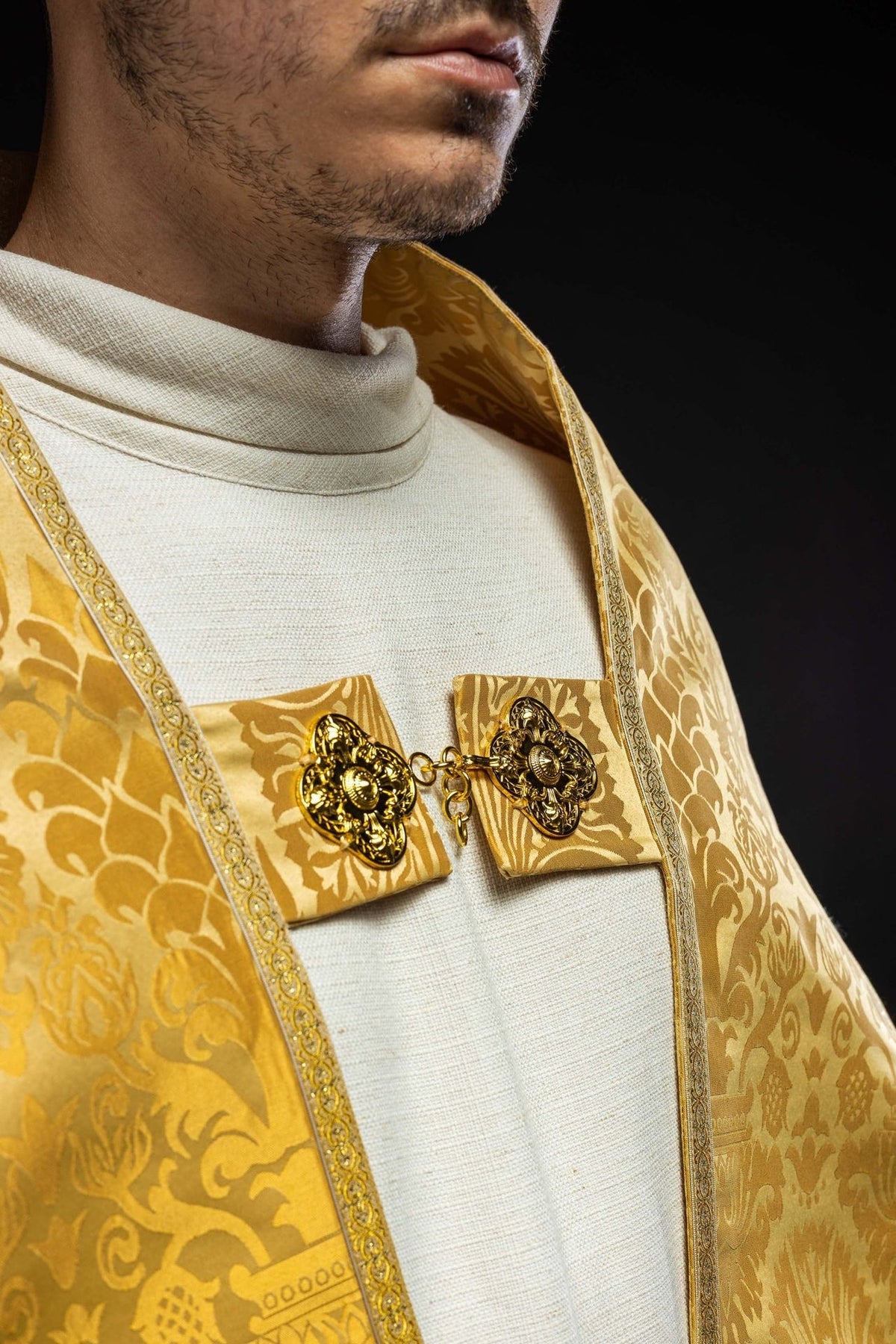 Gold cope collar and clasp close-up with floral jacquard fabric and decorative gold fastener