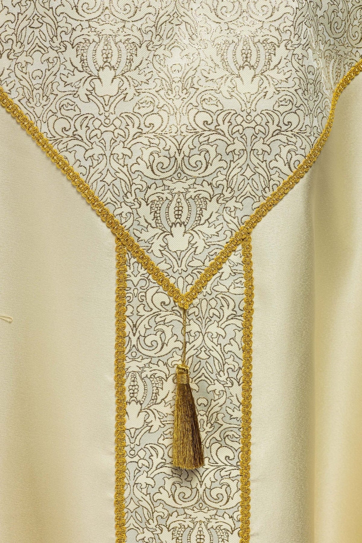 Ecru cope close-up showing ornate jacquard fabric, gold trim and tassel