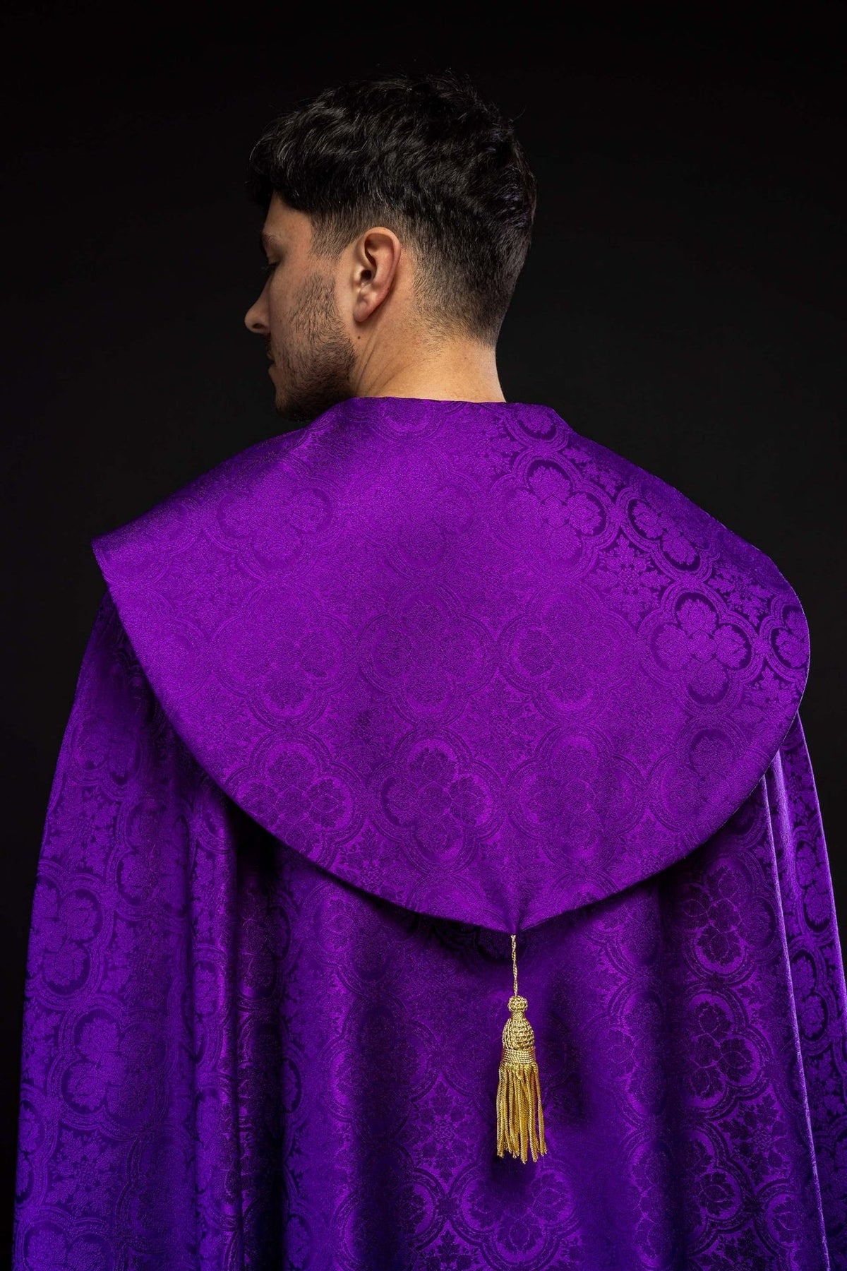 Purple cope shown from the back with a gold tassel and jacquard motifs