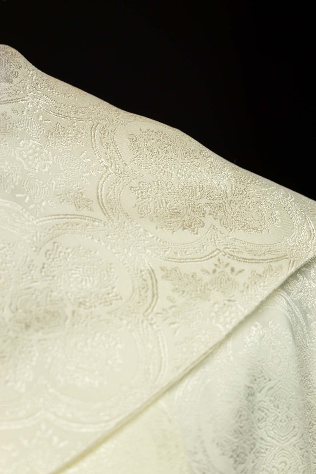 Ecru jacquard cope fabric close-up showing the ornate woven pattern
