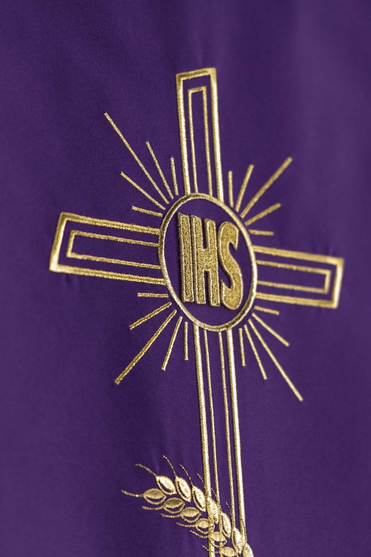 Church lectern cover close-up showing gold embroidered cross and IHS monogram on purple fabric