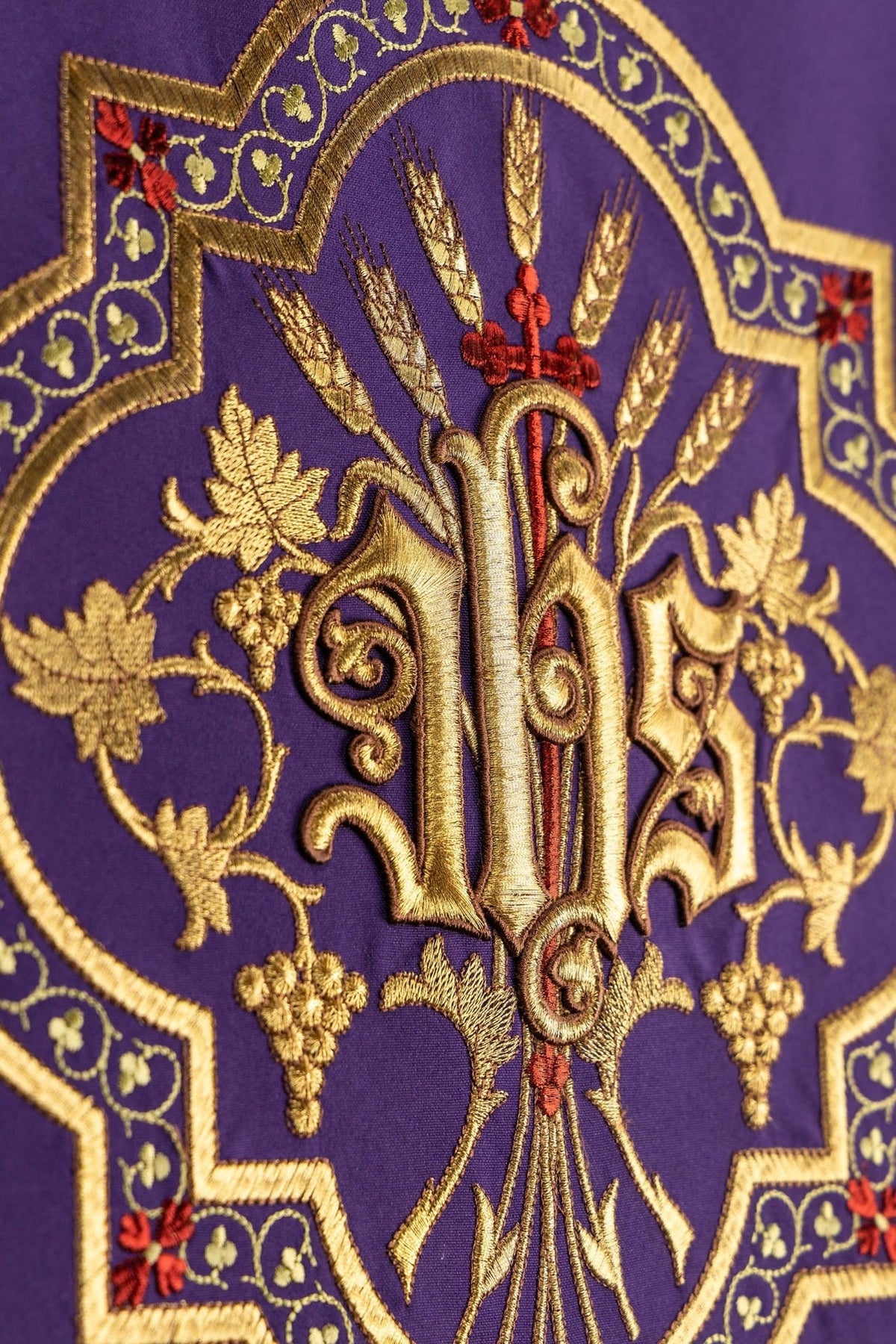 Purple church lectern cover close-up showing embroidered gold IHS monogram, wheat and vine details