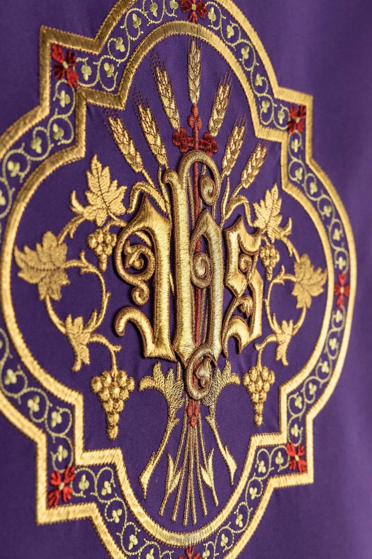 Purple church lectern cover close-up showing gold embroidery, wheat and vine surrounding the IHS monogram