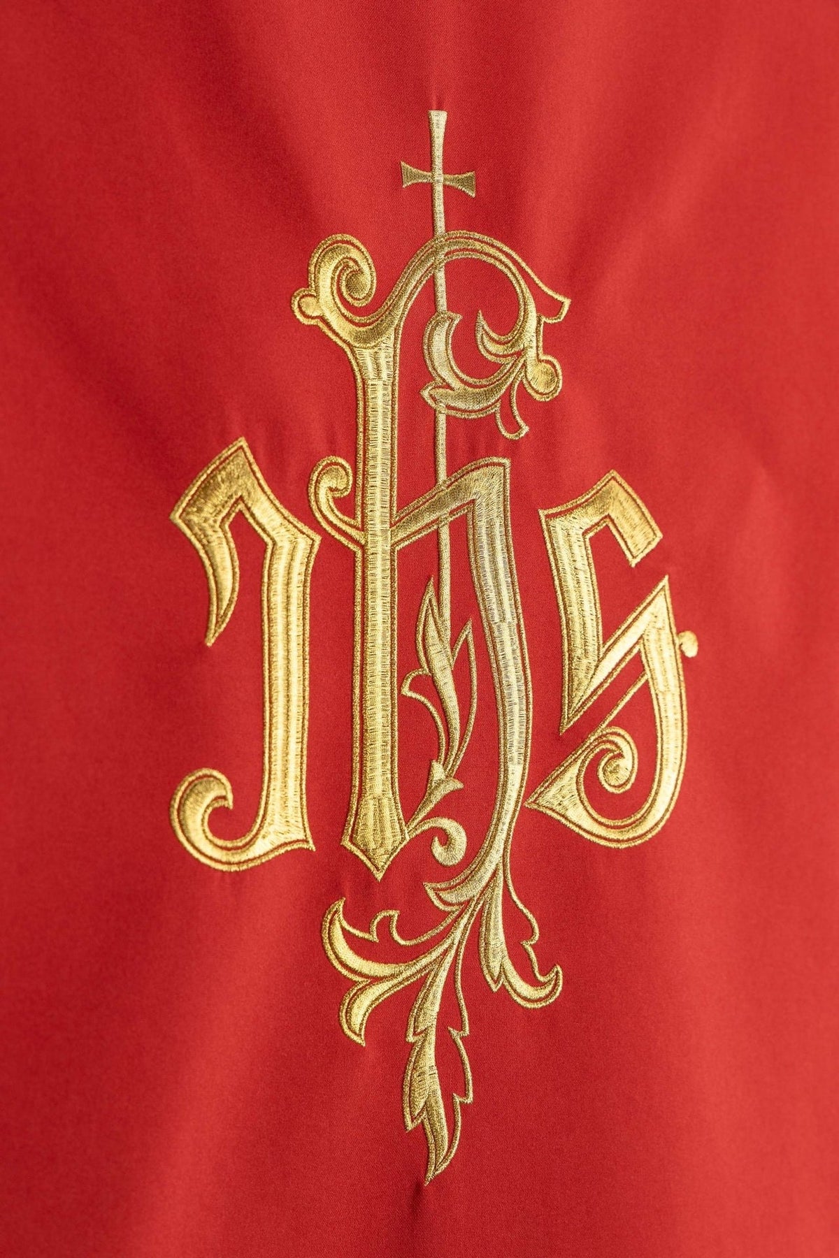 Red church lectern cover close-up showing gold embroidered IHS monogram
