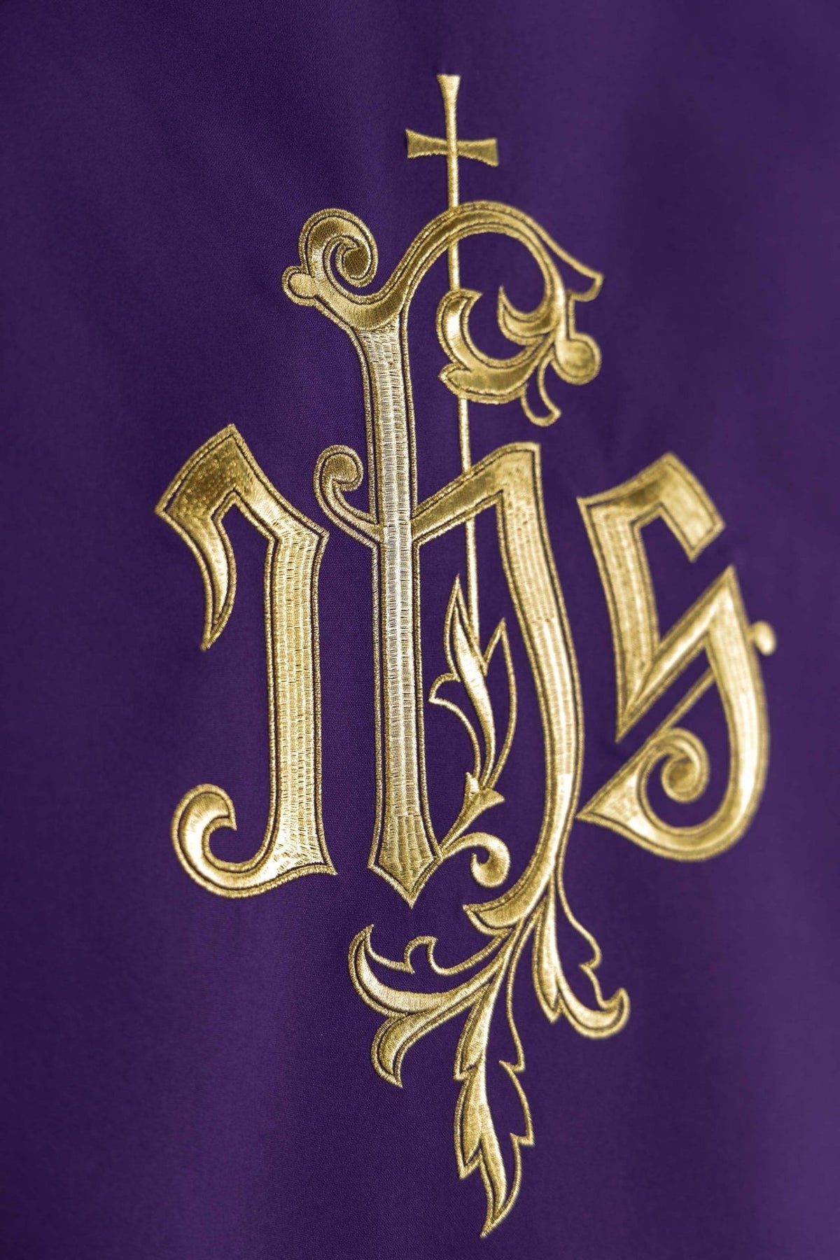Church lectern cover close-up showing gold embroidered IHS monogram on purple fabric