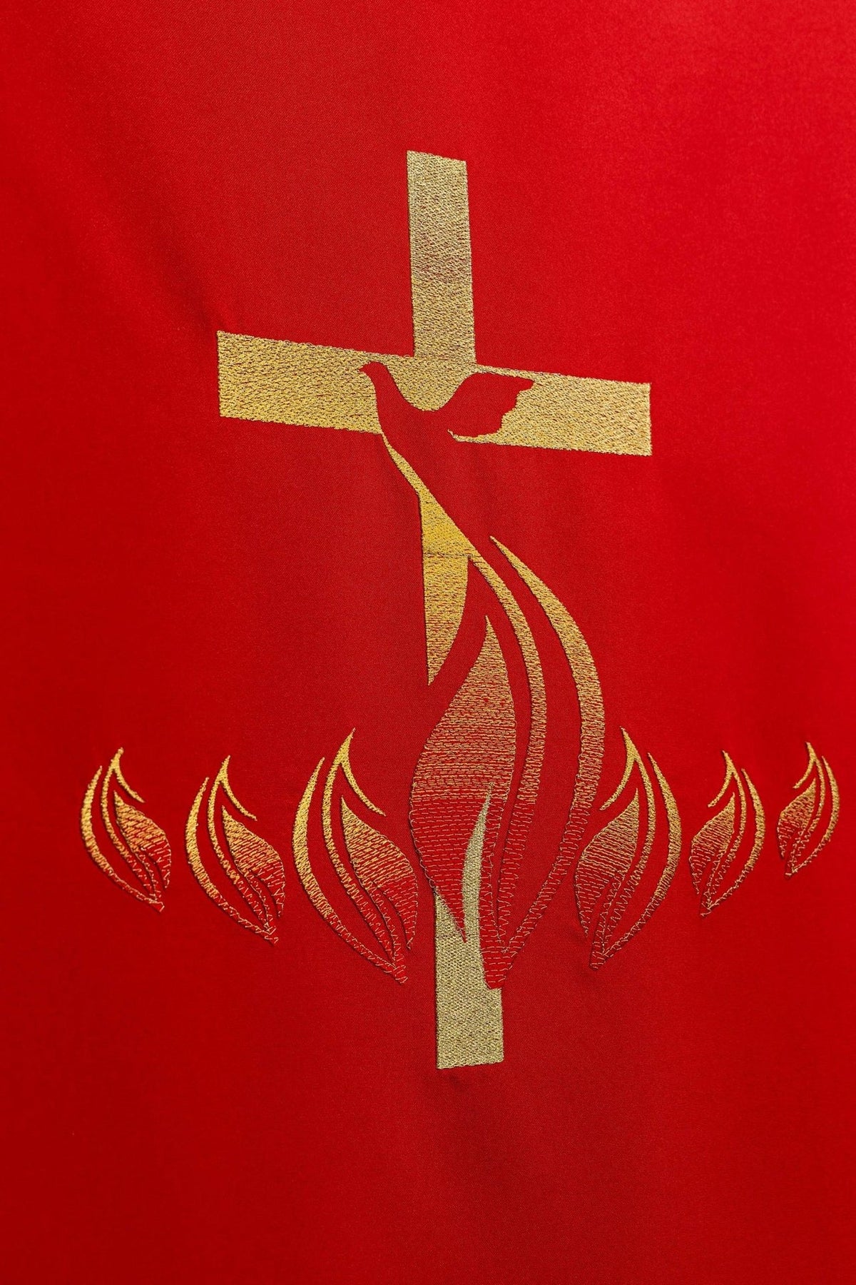 Red church lectern cover close-up showing gold cross, Holy Spirit dove and flames