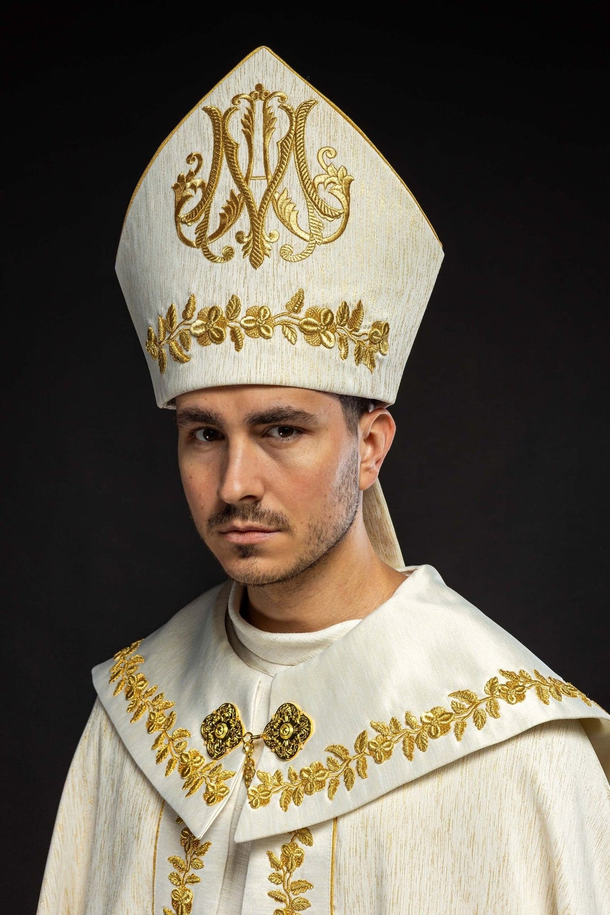 Ecru miter, front three-quarter view with gold Marian symbol and floral embroidery
