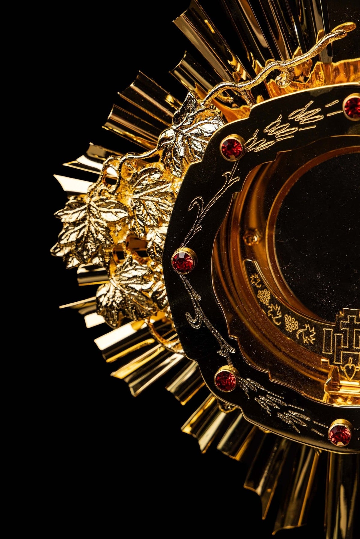 Catholic monstrance close-up of cross with red gemstone and surrounding radiant rays