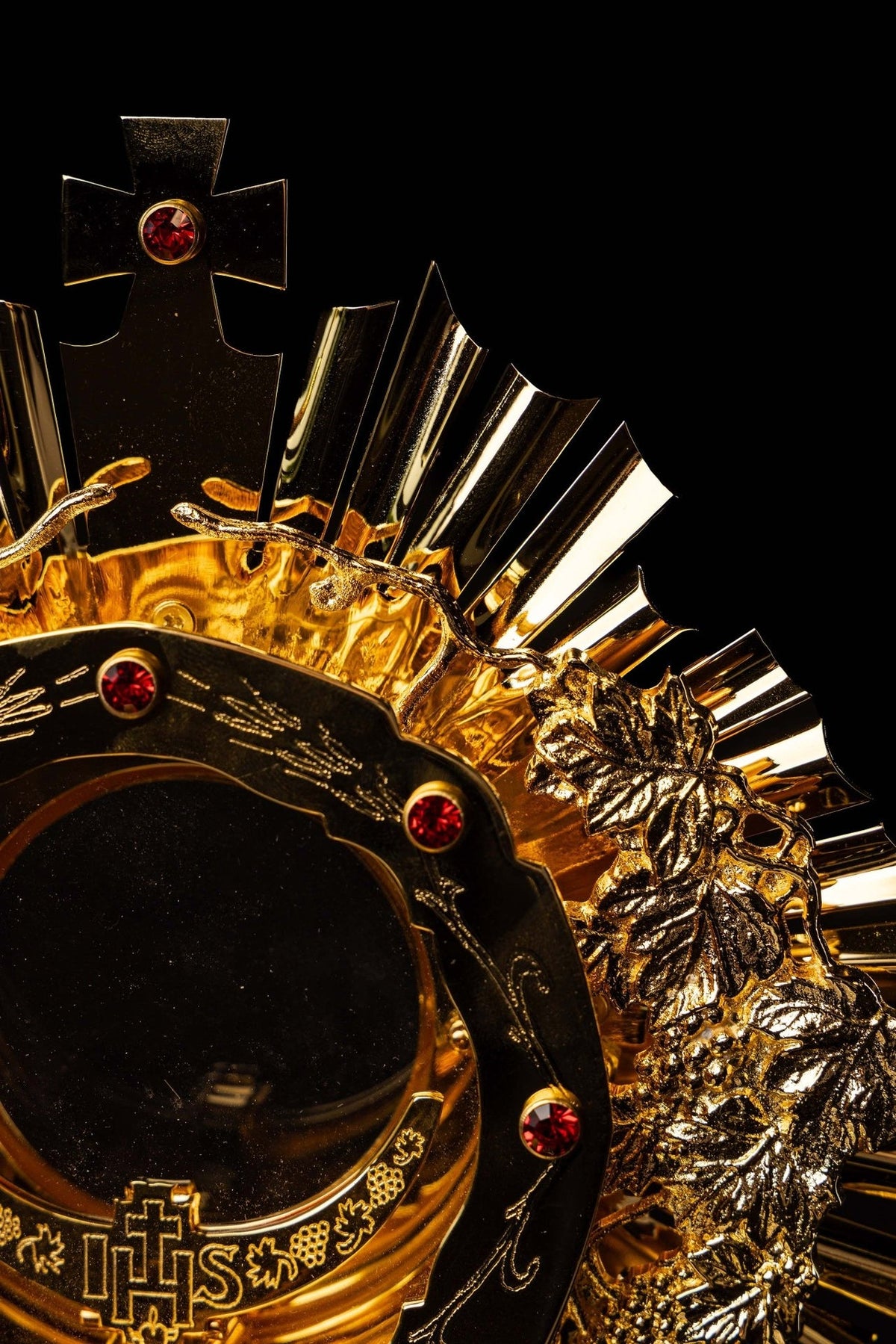 Catholic monstrance side close-up showing grapevine detail, red gemstones and radiant rays