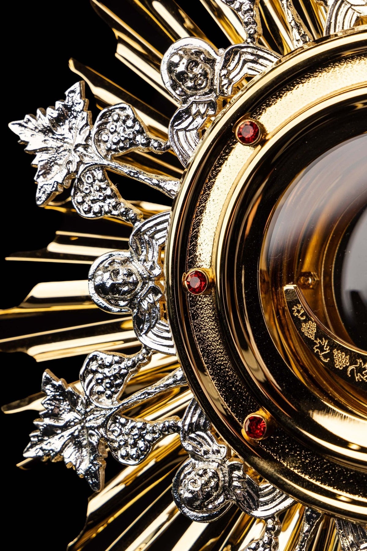 Monstrance close-up showing silver-tone grape and leaf ornaments around the gold rays