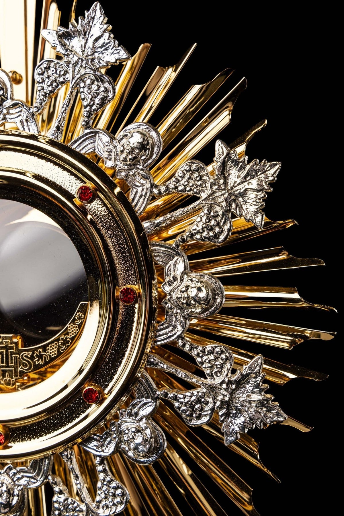 Monstrance side close-up of red stones, grape motifs and layered gold sunburst rays