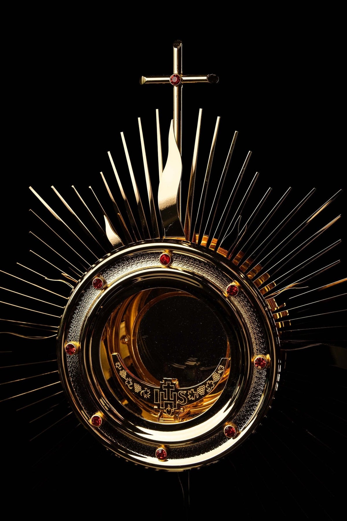 Gold-plated radiant monstrance close-up with cross, rays and red stones